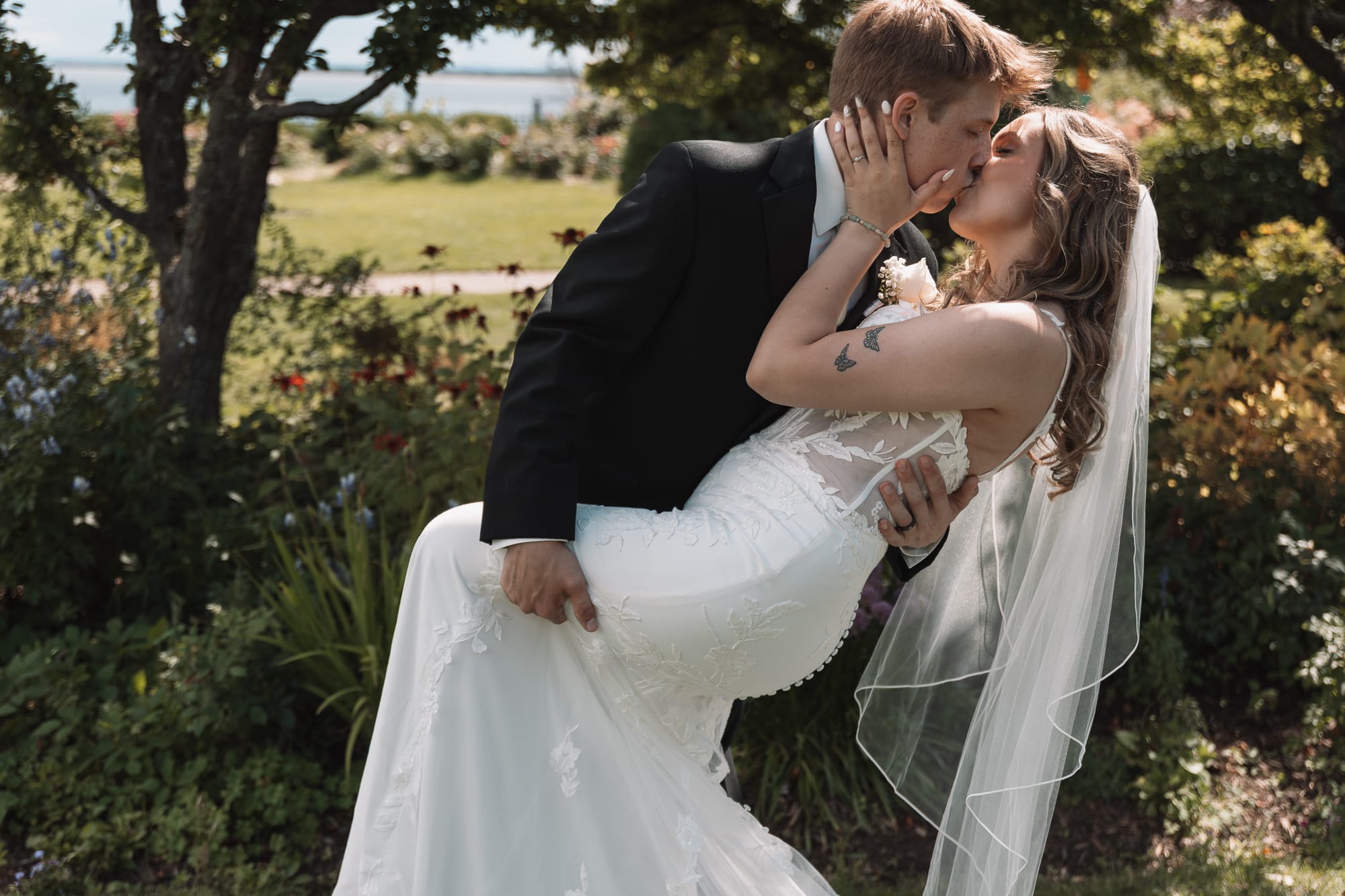 Bride and groom sharing a kiss in a lakeside garden on their wedding day
