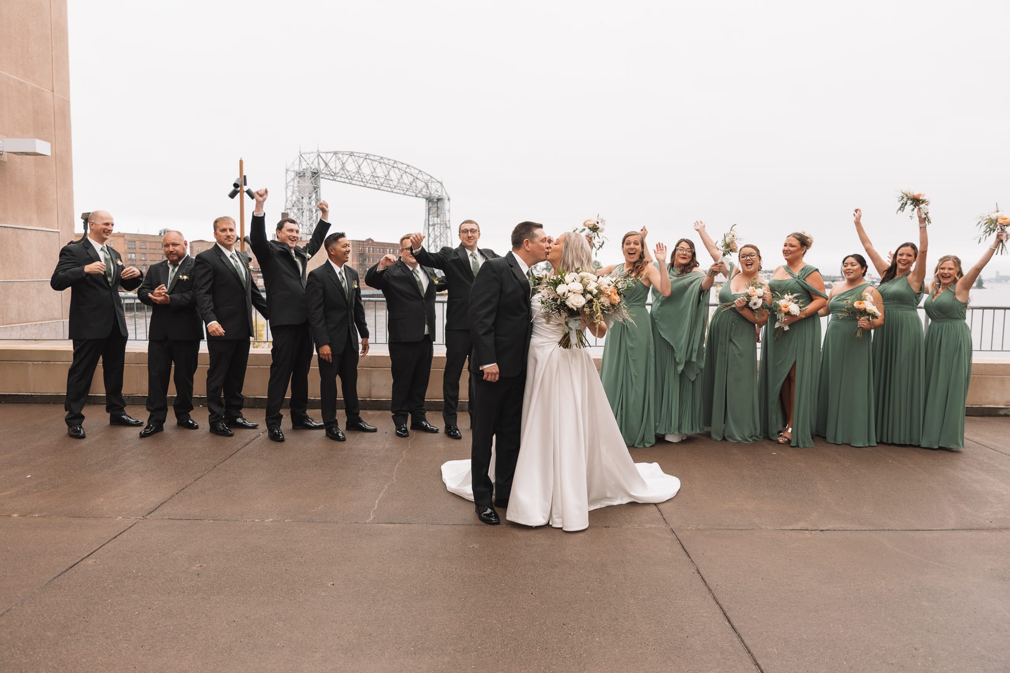 Wedding party celebrating with the couple by the Duluth Aerial Lift Bridge